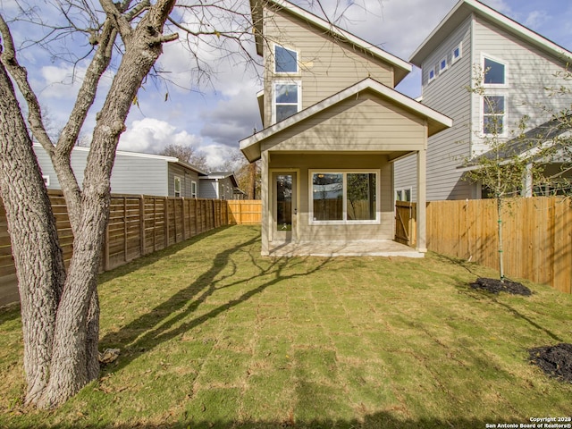 rear view of property with a fenced backyard, a yard, and a patio