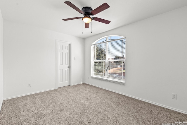 carpeted empty room with a ceiling fan and baseboards