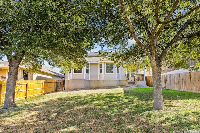 rear view of house featuring fence and a yard