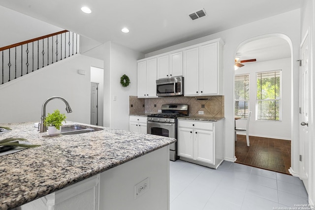 kitchen with light stone counters, arched walkways, visible vents, appliances with stainless steel finishes, and a sink