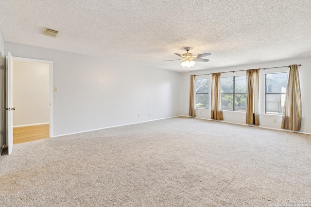 carpeted empty room with visible vents, ceiling fan, a textured ceiling, and baseboards