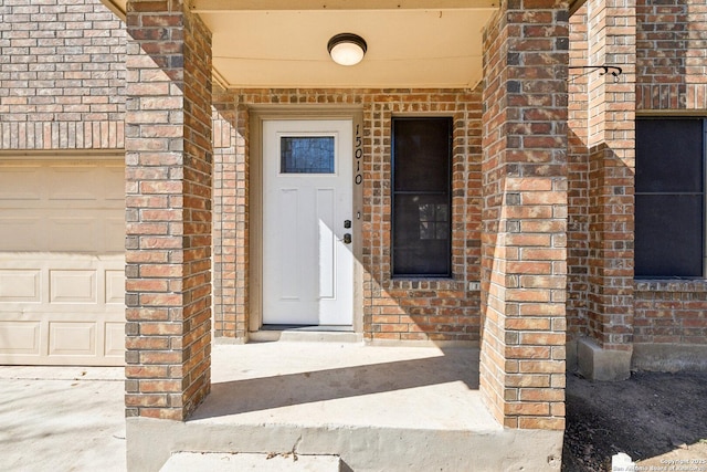 entrance to property with brick siding and an attached garage