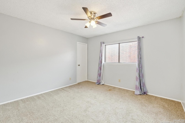 carpeted empty room with a ceiling fan, baseboards, and a textured ceiling