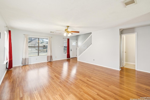 unfurnished living room with visible vents, baseboards, a ceiling fan, stairway, and light wood-type flooring