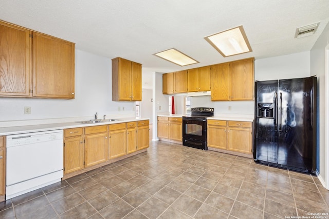 kitchen featuring visible vents, under cabinet range hood, light countertops, black appliances, and a sink