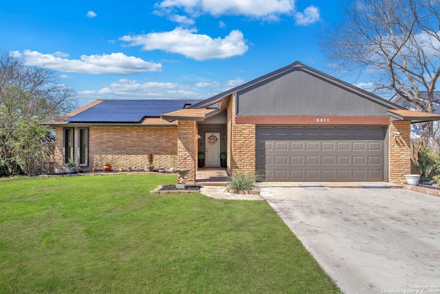 mid-century home with solar panels, a front lawn, concrete driveway, and brick siding