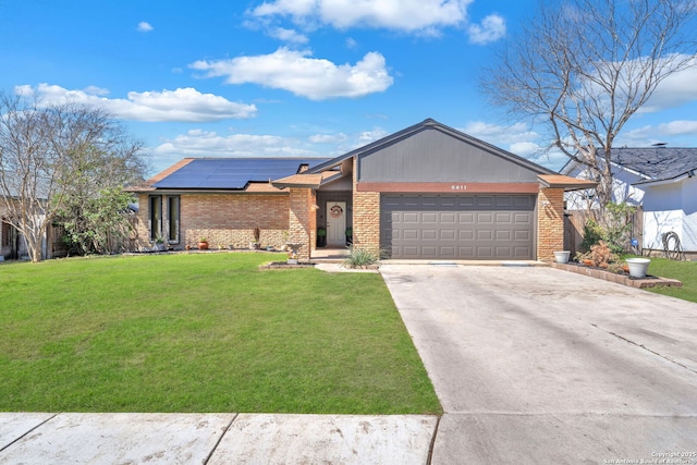 view of front facade featuring brick siding, solar panels, concrete driveway, an attached garage, and a front lawn