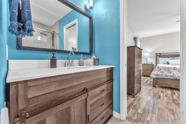 ensuite bathroom featuring wood finished floors, a stall shower, connected bathroom, and vanity