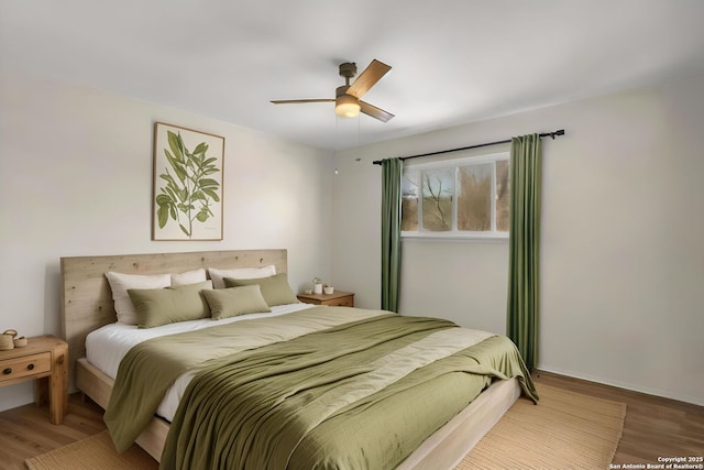 bedroom with ceiling fan, wood finished floors, and baseboards