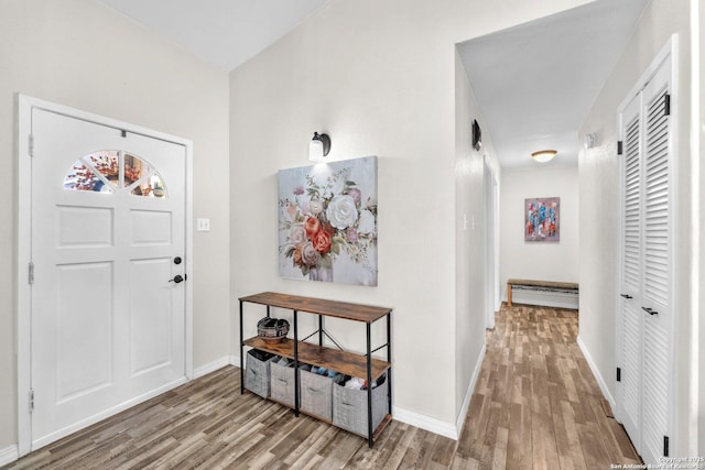 entryway featuring a baseboard radiator, baseboards, and wood finished floors