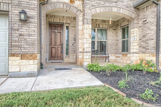 doorway to property with a garage, stone siding, and brick siding