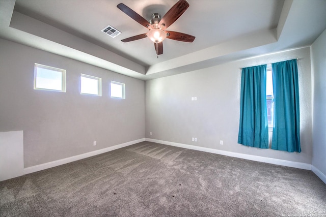 carpeted spare room with baseboards, visible vents, a raised ceiling, and a ceiling fan