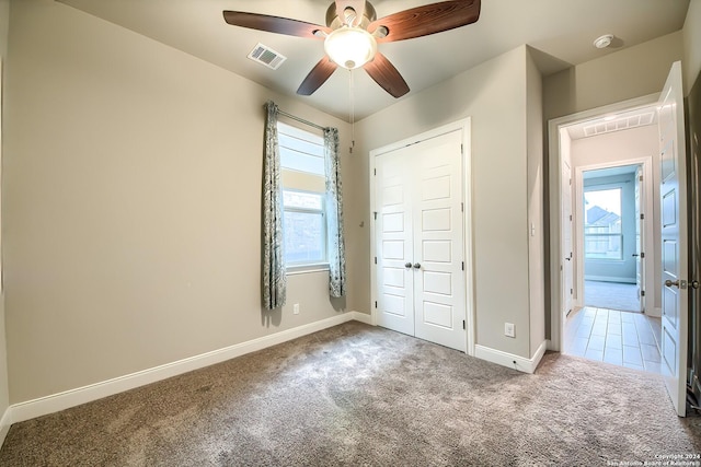 unfurnished bedroom with multiple windows, carpet, visible vents, and baseboards