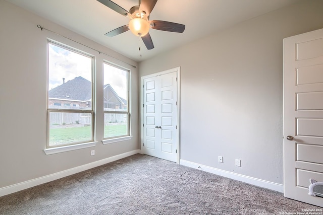 unfurnished bedroom featuring carpet floors, ceiling fan, baseboards, and a closet