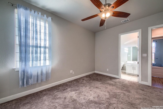 unfurnished bedroom featuring carpet floors, visible vents, ensuite bath, and multiple windows