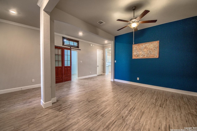 empty room featuring crown molding, wood finished floors, visible vents, and baseboards