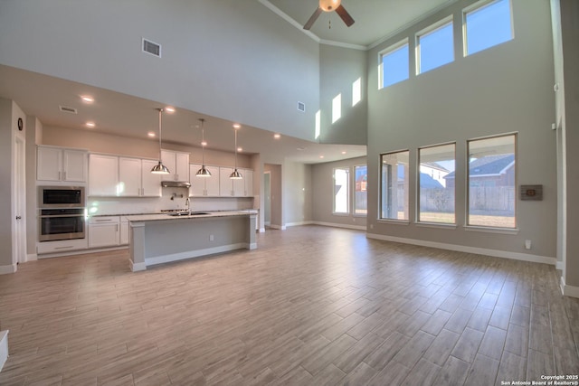 unfurnished living room featuring light wood-style floors, a wealth of natural light, a sink, and baseboards