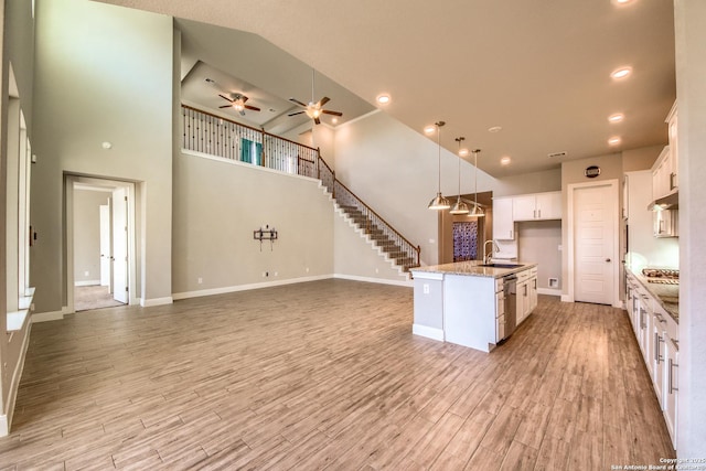 kitchen featuring light wood-type flooring, white cabinets, open floor plan, and a sink