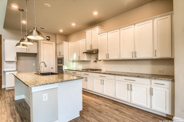 kitchen with wood finished floors, appliances with stainless steel finishes, a sink, and white cabinetry