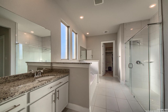 bathroom with visible vents, a spacious closet, a shower stall, vanity, and tile patterned floors