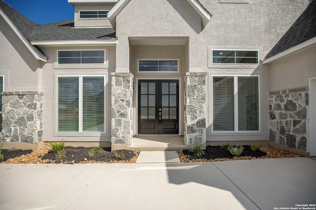 property entrance with stone siding, french doors, and stucco siding