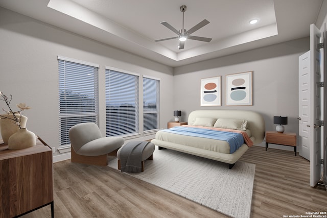 bedroom with a ceiling fan, recessed lighting, a raised ceiling, and wood finished floors