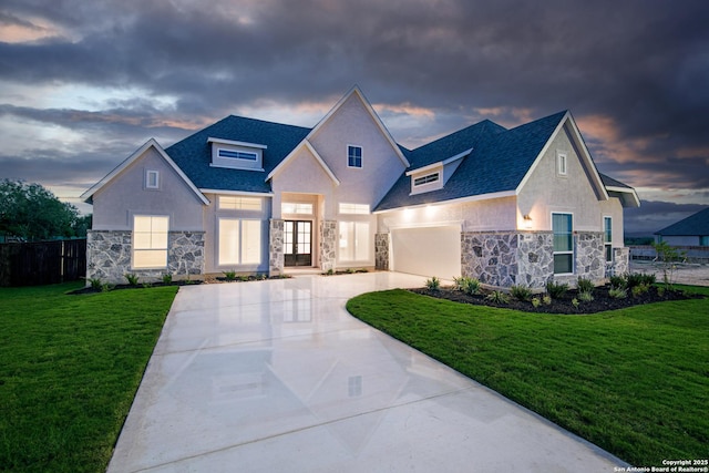 view of front facade featuring stone siding, a lawn, concrete driveway, and french doors