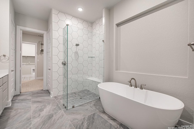 full bath with a soaking tub, a shower stall, vanity, and a spacious closet