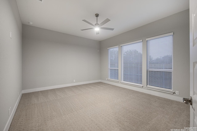 carpeted empty room featuring ceiling fan and baseboards