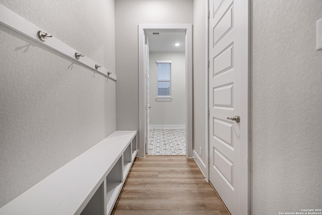 mudroom featuring light wood-type flooring and a textured wall