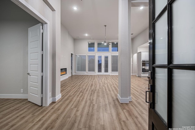 unfurnished living room with a glass covered fireplace, light wood-style flooring, and baseboards