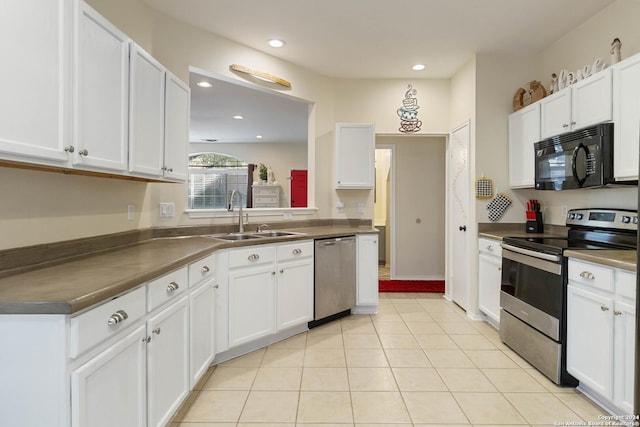 kitchen featuring light tile patterned floors, stainless steel appliances, dark countertops, white cabinetry, and a sink