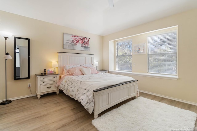 bedroom with ceiling fan, light wood-style flooring, and baseboards