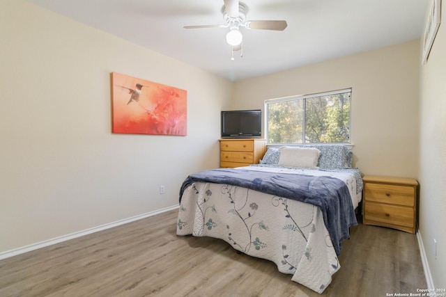 bedroom with a ceiling fan, baseboards, and wood finished floors