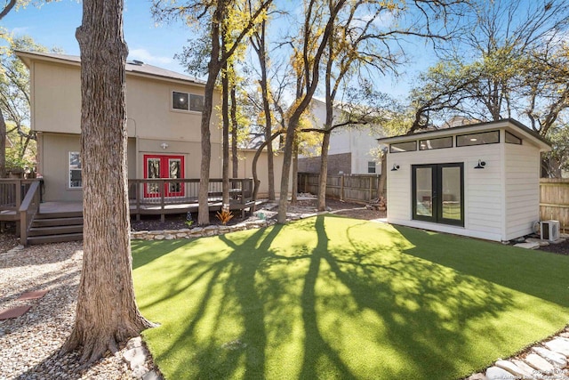 view of yard featuring french doors, a fenced backyard, an outdoor structure, and a wooden deck