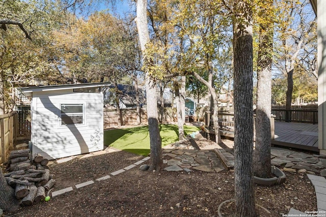 view of yard with a storage shed, a fenced backyard, a wooden deck, and an outdoor structure