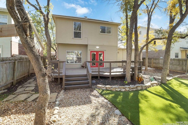 rear view of property featuring stucco siding, a fenced backyard, a wooden deck, and french doors