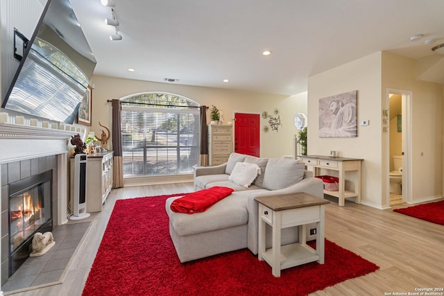 living room with recessed lighting, visible vents, light wood-style floors, a tiled fireplace, and track lighting