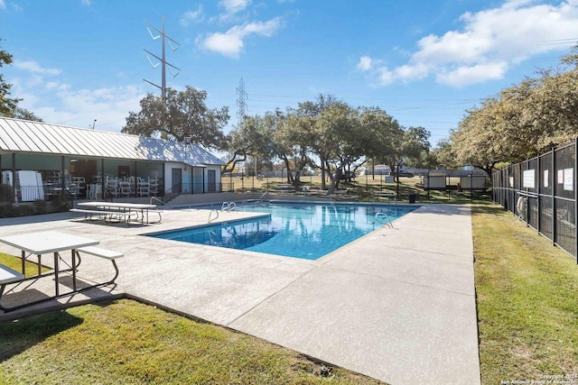 pool featuring a patio, a lawn, and fence