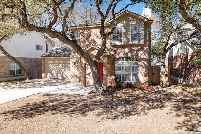 traditional-style home with brick siding, a chimney, concrete driveway, an attached garage, and fence