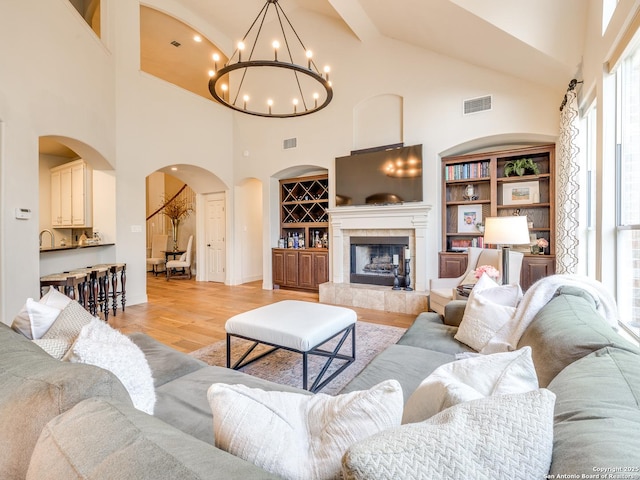 living room with light wood-style floors, a tile fireplace, visible vents, and built in features