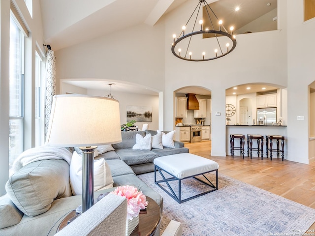 living room with high vaulted ceiling, light wood-type flooring, arched walkways, and recessed lighting