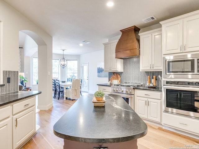 kitchen featuring appliances with stainless steel finishes, dark countertops, visible vents, and custom range hood