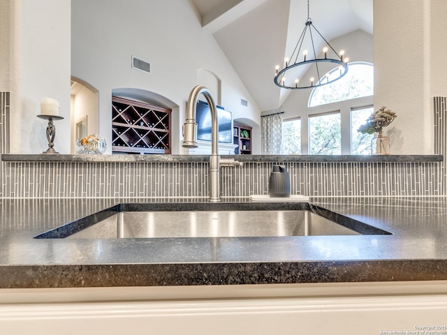 details featuring dark countertops, visible vents, decorative backsplash, and a sink