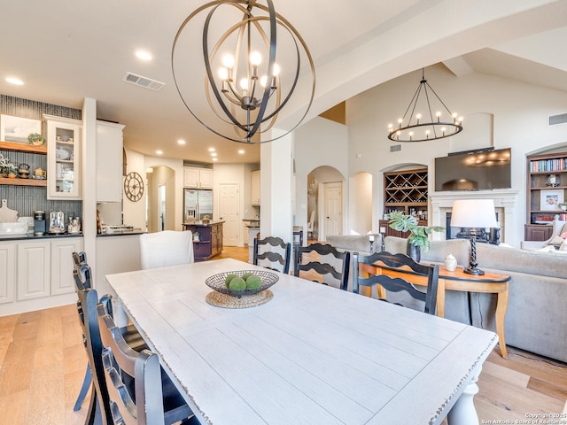 dining room featuring arched walkways, visible vents, a notable chandelier, and a fireplace