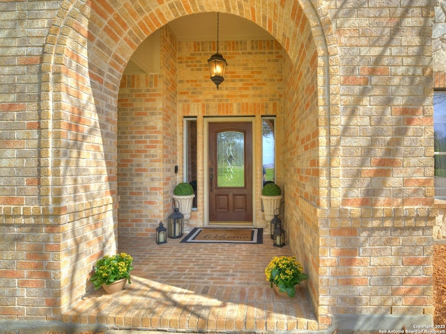 view of exterior entry featuring brick siding