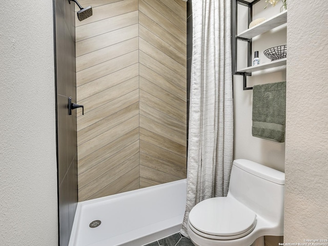 bathroom featuring a shower with curtain, a textured wall, and toilet