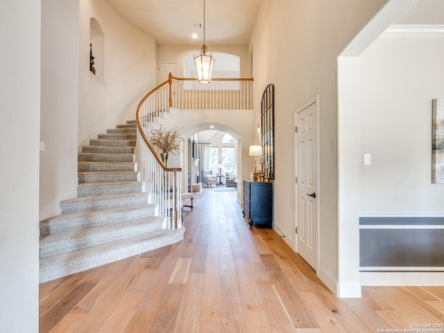 entrance foyer featuring a high ceiling, hardwood / wood-style flooring, stairway, and arched walkways