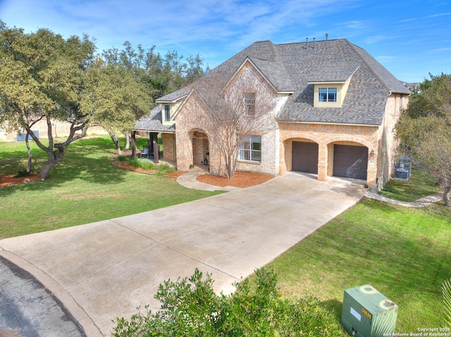 french country home featuring brick siding, stone siding, concrete driveway, roof with shingles, and a front yard