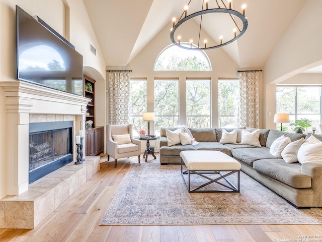 living room with a fireplace, plenty of natural light, a notable chandelier, and hardwood / wood-style floors